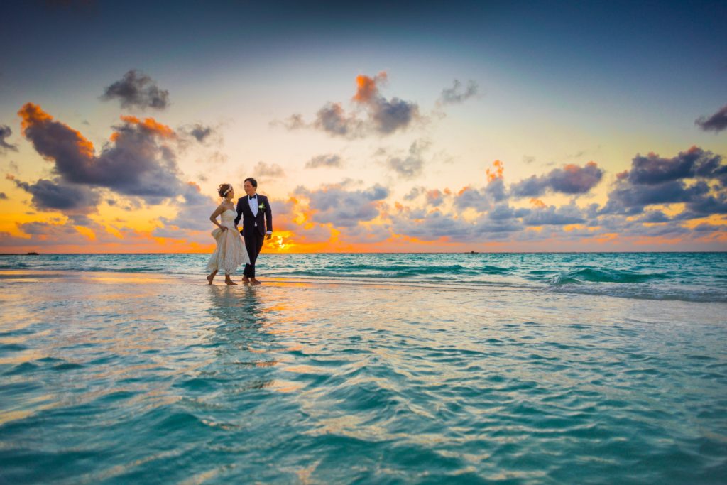 Destination Wedding Couple Walking Together On Beach During Sunset